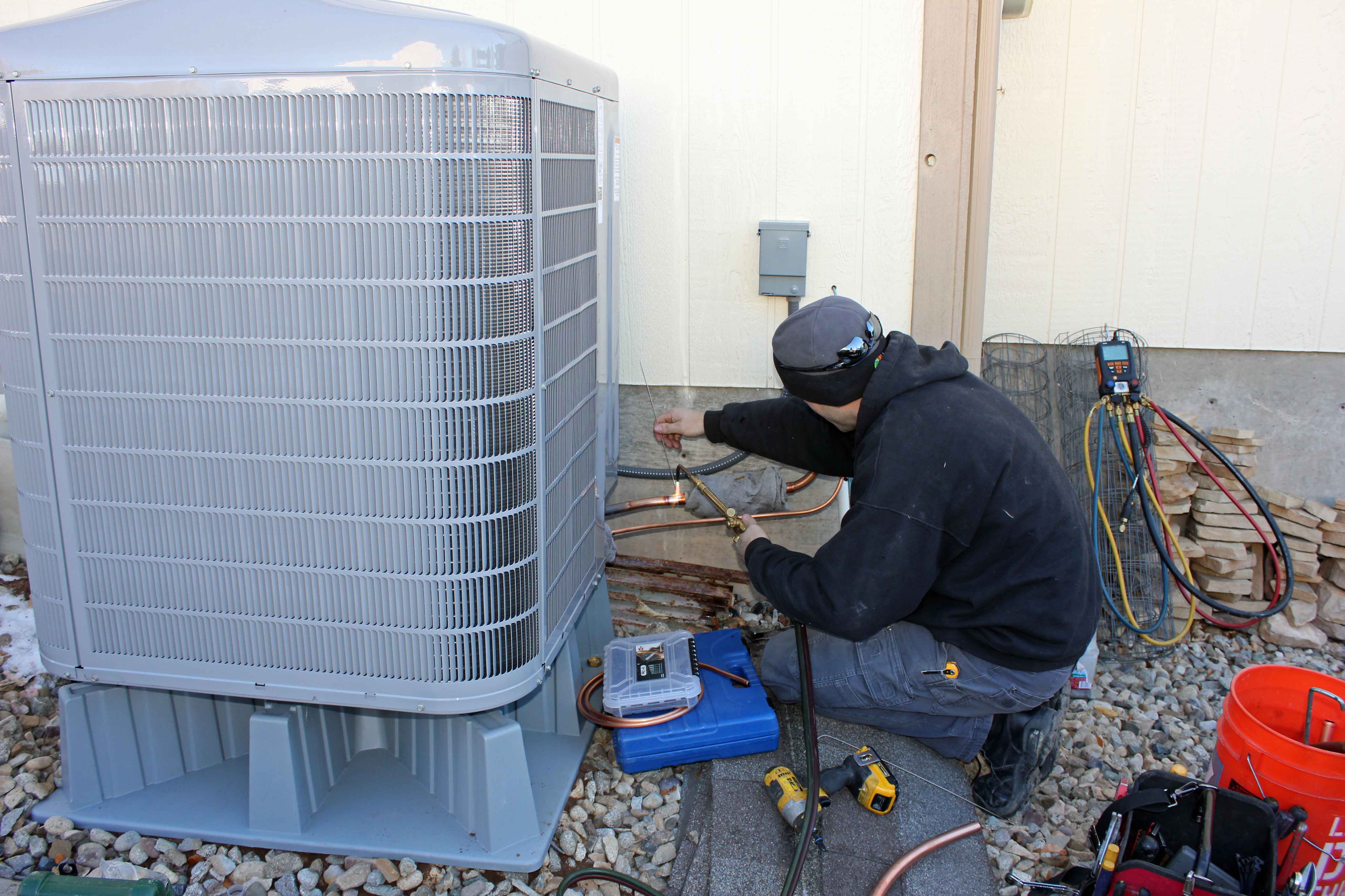 heat pump condenser being installed outside home